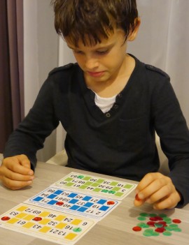enfant jouant au loto et marquant les chiffres tirés au sort sur ses cartons de jeux