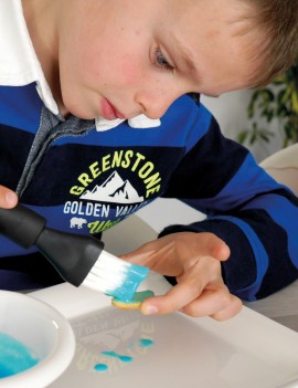 enfant posant du colorant sucré bleu sur un petit sablé