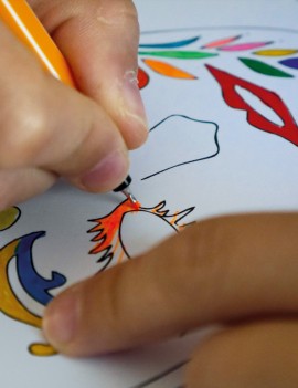 Un enfant coloriant une carte postale avec un feutre