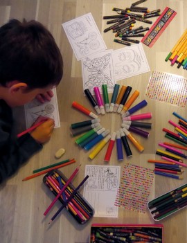 Décoration des cartes postales, un enfant colorie une carte autour de lui des feutre, des strass des stickers