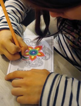 Une enfant coloriant une carte postale avec un feutre, mandala