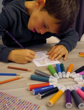 Décoration des cartes postales par un enfant coloriant un masque avec un feutre