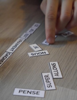 enfant jouant au "devine la phrase" et tentant de reconstituer une phrase à partir de mots mélangés